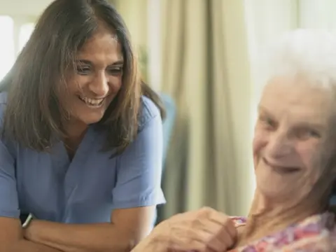 Caregiver smiling with an elderly client at home